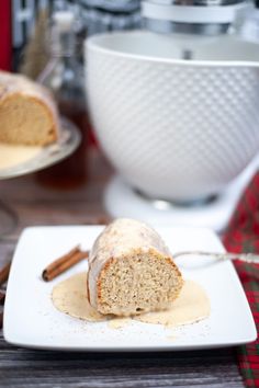 a piece of cake sitting on top of a white plate next to a bowl and cinnamon sticks