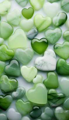 many green and white hearts are arranged in the shape of heart shaped stones on a white surface