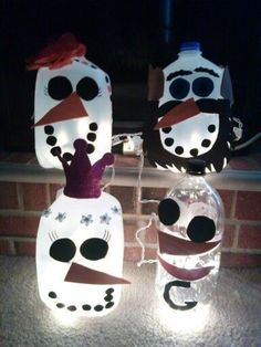 two snowmen made out of plastic bottles sitting on top of a brick wall next to each other