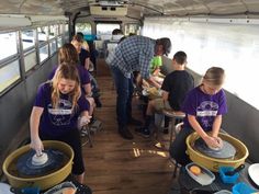 some people are washing dishes in large buckets on a boat while others look on