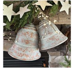 two bells hanging from a christmas tree with stars on the wall behind them and greenery