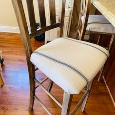 a wooden chair sitting in front of a counter top next to a stool with a cushion on it