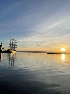 the sun is setting over an ocean with ships