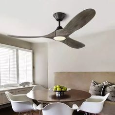 a ceiling fan in the middle of a dining room table with chairs and fruit on it