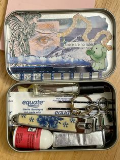 an open tin with various items in it on a wooden table next to a pair of scissors