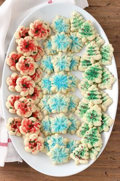 a white plate topped with cookies covered in frosting and sprinkles on top of a wooden table