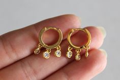 Dainty shaker earrings.Three round bezel set crystals dangle from small gold huggie hoops. Dimensions: earrings measure approximately 1.3 cm x 1.8 cm. Gold plated. Clear crystals. Huggie snap closure. Comes nicely wrapped in a jewelry box and ready to be gifted! All you need to do is put it in a gift bag. If you would like a note to be included in the package, just put your request in your order notes and I will make sure to include it! Affordable jewelry makes for a sweet gift for your best fri Dainty Round Hoop Earrings With Dangling Charms, Shaker Earrings, Small Gold Hoops, Clear Crystals, Affordable Jewelry, Huggie Hoop Earrings, Modern Earrings, Gold Hoops, Chain Earrings