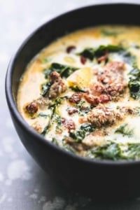 a close up of a bowl of soup with meat and spinach in it on a table