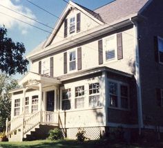 a large gray house sitting on top of a lush green field