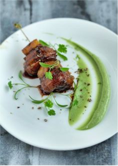 a white plate topped with meat covered in sauce and garnished with cilantro