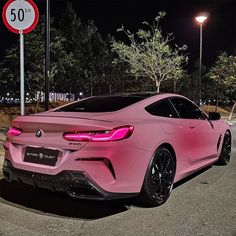 a pink sports car parked in front of a speed limit sign