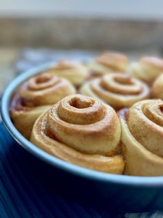 a blue bowl filled with cinnamon rolls on top of a table