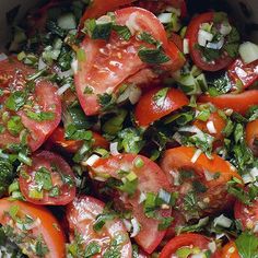 a bowl filled with lots of different types of tomatoes and green leaves on top of it