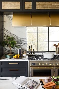 a kitchen with marble counter tops and stainless steel oven hoods, surrounded by blue cabinets