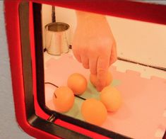 a person is placing eggs on top of each other in front of a red mirror