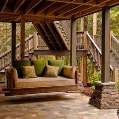 a couch sitting under a covered porch next to a stair case and stone flooring