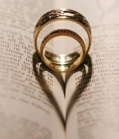 two wedding rings casting a heart shape on top of an open book with the words love cher