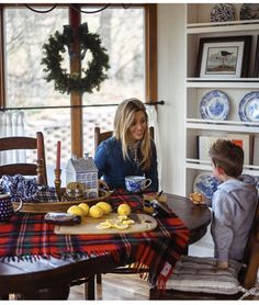 a woman sitting at a table with a little boy