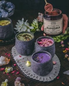 two cups filled with different colored liquids on top of a table next to flowers