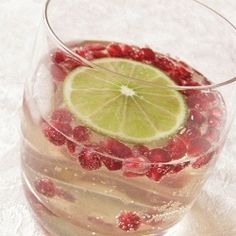 a glass filled with raspberries and lime on top of a white tablecloth