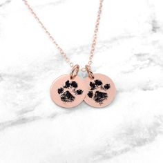 two paw prints are shown on the back of this rose gold necklace