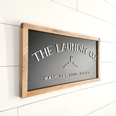 the laundry co wash dry fold sign mounted on a white brick wall with wood frame