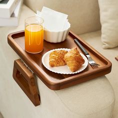 a tray with two croissants and orange juice on it next to a cup