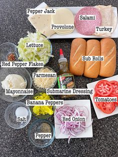 the ingredients for this sandwich are displayed in separate bowls and on separate trays, including tomatoes, peppers, lettuce, turkey, red onions, mayonnaine, ketchup, hot dog