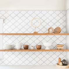 shelves with bowls and plates on them in a room that has white wallpaper behind it