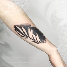 a person's arm with a black and white leaf tattoo on the left forearm