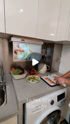 a woman standing in front of a washing machine with food on the counter next to her