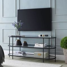 a flat screen tv mounted to the side of a wall next to a vase with flowers