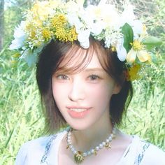 a young woman wearing a flower crown on her head and pearls necklace around her neck