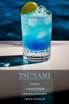 a blue cocktail with a lime slice on the rim in front of a body of water