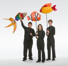 three people are holding up fish and balloons