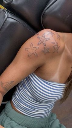 a woman with a star tattoo on her arm and shoulder, leaning against a black leather chair