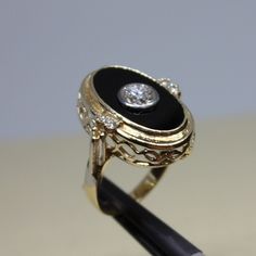 Fancy, vintage ring for women, in excellent condition made of 14k yellow gold, solid. Center approximately 0,80ctw plus, round shaped with approximate color F and VS1 clarity, burnished on on the center of Onyx, sized 11x18mm flat Onyx, complimented by a 4 small round shaped diamonds, two on each side, on prongs, approximate weight of which is 0,20ctw. Weight of the item is 6.7g, size 7 could be changed to. Please look at the all pictures and if you have any questions, ask, we will be happy to assist you. Ring will come in a very nice gift box, that will make it look even more special for asomeone you love. Thank you for shopping with us. Victorian Black Enamel Rings For Anniversary, Victorian Black Enamel Anniversary Rings, Elegant Yellow Gold Diamond Ring With Black Enamel, Vintage Oval Diamond Ring With Polished Finish, Black Oval Cluster Ring For Anniversary, Formal Yellow Gold Diamond Ring With Black Enamel, Antique Black Filigree Ring For Formal Occasions, Round Black Enamel Diamond Ring For Anniversary, Black Enamel Diamond Anniversary Ring