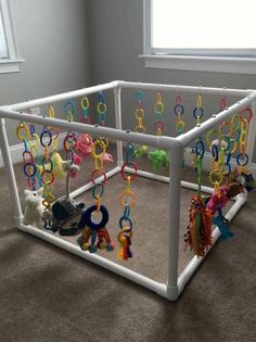 a playpen with toys hanging from it's sides in a room next to a window