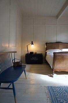 a bed sitting next to a blue table on top of a hard wood floor in a bedroom