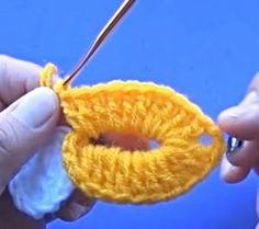 two hands are holding yarn and crochet together to make a ring ornament