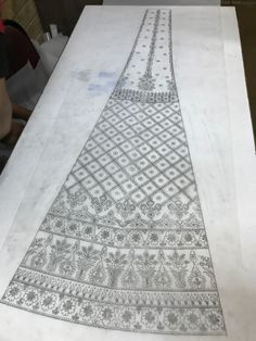 an intricately designed piece of cloth is being worked on by a person at a table