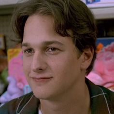 a close up of a person in a room with stuffed animals on the wall behind him