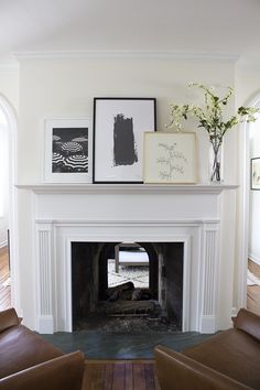 a living room with a fire place and pictures on the fireplace mantel above it