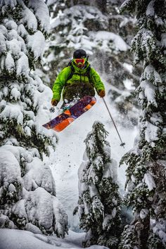 a man flying through the air while riding skis on top of snow covered trees