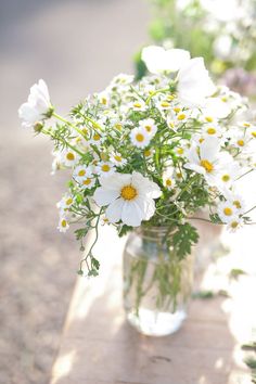 a glass vase filled with white and yellow flowers