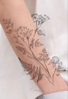 a woman's arm with flowers and leaves drawn on the back of her arm