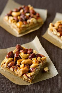 four pieces of food sitting on top of brown paper napkins with nuts in them