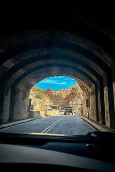 a car driving through a tunnel with mountains in the backgrouund and blue sky above