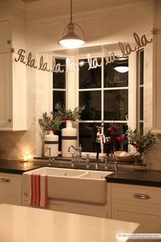 a kitchen filled with white cabinets and black counter tops next to a window covered in christmas decorations