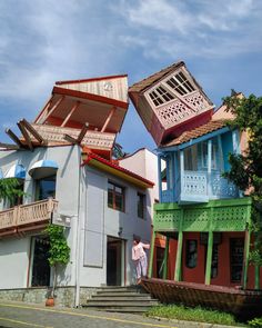 a person standing in front of some colorful houses with their doors open and the roof ripped off